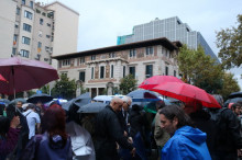 Els concentrats amagats de la pluja sota els paraigües durant l'acte reivindicatiu davant la delegació del govern a Barcelona