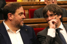 El president de la Generalitat, Carles Puigdemont, i el vicepresident, Oriol Junqueras, parlen durant el ple del Parlament