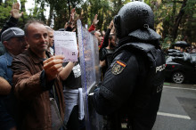 Un votant exhibeix una papereta davant d'un agent de la policia espanyola l'1-O