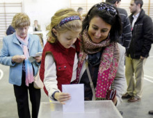 Una nena diposita el vot de la mare en un col·legi electoral de Vigo.