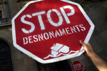 Un activistes de la PAH amb pancartes demanant que s'aturin els desnonaments, en una imatge d'arxiu