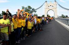 Els participants a la cadena humana enllacen les seves mans sobre el pont penjant d'Amposta