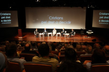 Vista general de l'escenari de l'acte, amb el coordinador del Pacte Nacional pel Dret a Decidir, Joan Rigol, la monja Victòria Molins, el teòleg Xavier Morlans, i el comissari del Tricentenari, Miquel Calçada