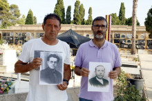 Pla mitjà del president de l'associació de familiars de víctimes del franquisme de la Fossa 113 de Paterna Santi Vallès (dreta) i un altre dels familiars, Miguel Esteve, posen al cementiri amb fotografies dels seus avantpassats