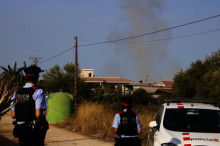 Pla mig de la columna de fum amb dos agents dels Mossos d'Esquadra d'esquena durant la detonació controlada
