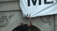Imatge d'un jove intentant arrencar la pancarta de "Democràcia"
