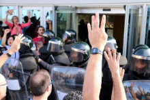 Pla detall de mans mostrant quatre dits davant dels antiavalots de la Guàrdia Civil