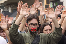 Primer pla d'un estudiant amb la cara tapada i mans aixecades al voltant en la manifestació en defensa del referèndum