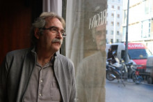 L'escriptor Jaume Cabré mirant a través d'un vidre el carrer, amb el seu reflex, durant una entrevista amb l'ACN