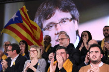 Els candidats de JxCat, amb una imatge del cap de llista, Carles Puigdemont de fons