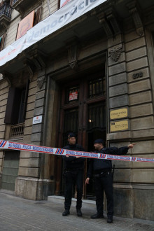 Dos agents dels Mossos d'Esquadra custodien la porta de la seu d'Òmnium Cultural, on la Guàrdia Civil hi duu a terme escorcolls