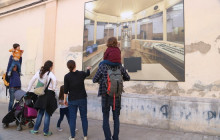 Una família amb nens observa una fotografia mural que mostra l'interior de l'antiga presó Model de Barcelona