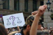 Un interrogant en línia darrere del símbol de la justícia a la manifestació de rebuig a la sentència de La Manada