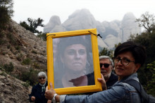 Una participant a la cadena humana mostra la fotografia d'Anna Gabriel sota les muntanyes de Montserrat