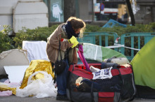 Una dona recollint el seu equipatge durant el desallotjament de l'acampada dels sense sostre a la Plaça Catalunya