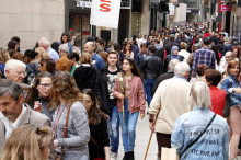L'Eix Comercial de Lleida, ple de gent passejant, i una parella al mig amb una rosa blanca