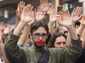 Primer pla d'un estudiant amb la cara tapada i mans aixecades al voltant en una manifestació