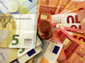 Una pila de bitllets amb una torre de monedes d'euro al centre