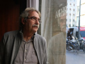 L'escriptor Jaume Cabré mirant a través d'un vidre el carrer, amb el seu reflex, durant una entrevista amb l'ACN