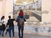 Una família amb nens observa una fotografia mural que mostra l'interior de l'antiga presó Model de Barcelona