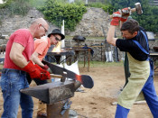 Pla tres quarts de tres forjadors en plena feina, amb els malls i el ferro roent