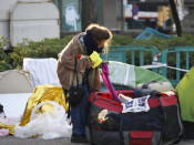 Una dona recollint el seu equipatge durant el desallotjament de l'acampada dels sense sostre a la Plaça Catalunya